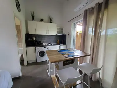 a kitchen with a table and chairs and a microwave at Mini villa 200 mètres de la plage de Santa Guilia in Porto-Vecchio