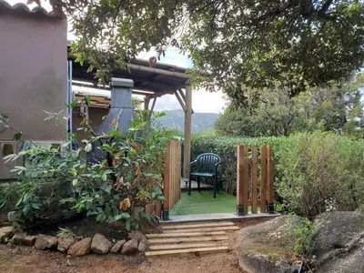a wooden porch with a chair in a garden at Mini villa 200 mètres de la plage de Santa Guilia in Porto-Vecchio