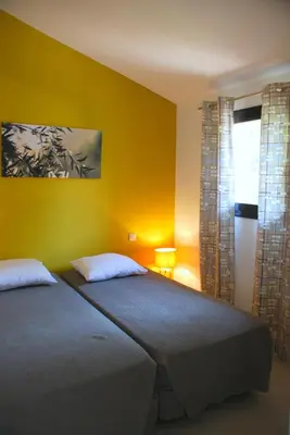 a bedroom with a bed and a yellow wall at Mini Villa Santa in Porto-Vecchio