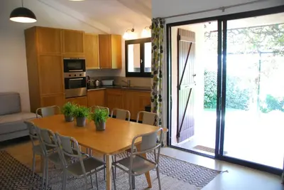 a kitchen and dining room with a wooden table and chairs at Mini Villa Santa in Porto-Vecchio
