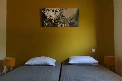 two beds in a room with a yellow wall at Mini Villa Santa in Porto-Vecchio