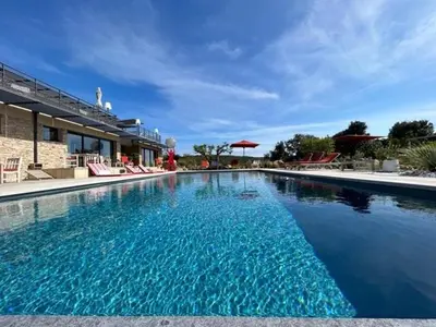 a swimming pool with blue water in front of a building at Villa With Private Pool And Golf Near Bonifacio in La Crociata