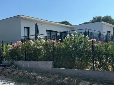 a white house with a fence and flowers at magnifique villa au calme avec superbe piscine in Figari