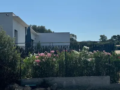 a fence with flowers in front of a house at magnifique villa au calme avec superbe piscine in Figari