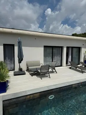 a patio with chairs and an umbrella next to a pool at magnifique villa au calme avec superbe piscine in Figari