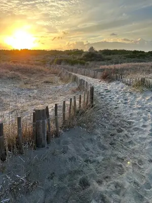 a fence on the beach with the sunset in the background at Villa Caline, 4 chambres, lotissement calme et proche mer in Lucciana