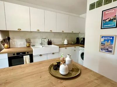 a kitchen with white cabinets and a table with vases on it at Villa Caline, 4 chambres, lotissement calme et proche mer in Lucciana