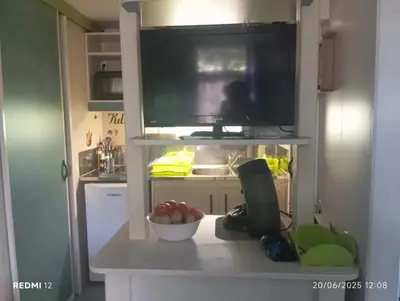 a kitchen with a television and a bowl of fruit on a counter at Bungalow charmant à Sorbo-Ocagnano avec jardin in Sorbo-Ocagnano