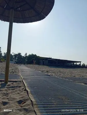 a beach with an umbrella and a sidewalk at Bungalow charmant à Sorbo-Ocagnano avec jardin in Sorbo-Ocagnano