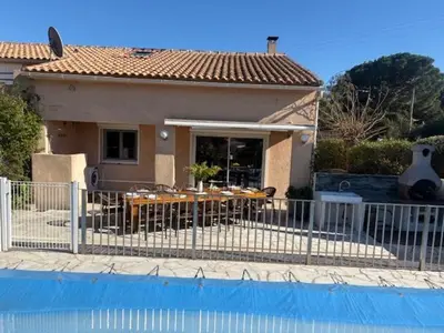 a house with a table and chairs next to a pool at Villa les Palmiers pool spa view of Bavella in Sainte-Lucie de Porto-Vecchio