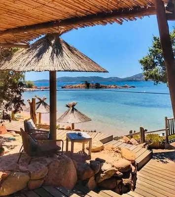 a beach with chairs and an umbrella and the water at Villa les Palmiers pool spa view of Bavella in Sainte-Lucie de Porto-Vecchio