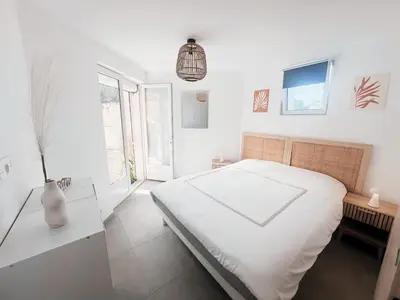 a white bedroom with a bed and a vase on a table at Appartement T3 vue mer et coucher de soleil sur les Îles Sanguinaires - climatisé in Pietrosella