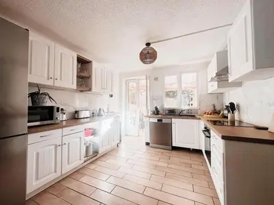 a kitchen with white cabinets and a wooden floor at Appartement T3 vue mer et coucher de soleil sur les Îles Sanguinaires - climatisé in Pietrosella