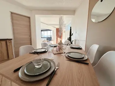 a dining room table with plates and glasses on it at Appartement T3 vue mer et coucher de soleil sur les Îles Sanguinaires - climatisé in Pietrosella