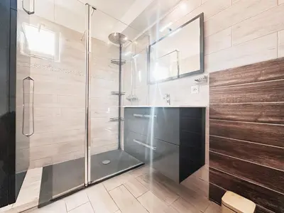 a glass shower in a bathroom with wooden walls at Appartement T3 vue mer et coucher de soleil sur les Îles Sanguinaires - climatisé in Pietrosella