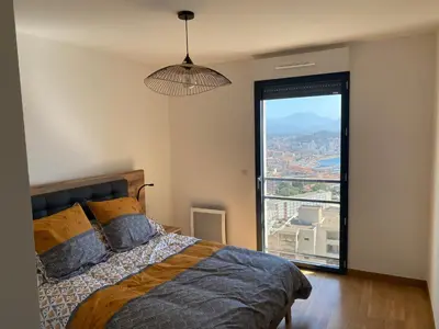 a bedroom with a bed and a large window at appartement ajaccio in Ajaccio
