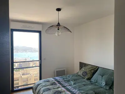 a bedroom with a bed and a large window at appartement ajaccio in Ajaccio