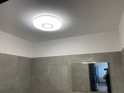 a person taking a picture of a bathroom with a light at appartement ajaccio in Ajaccio