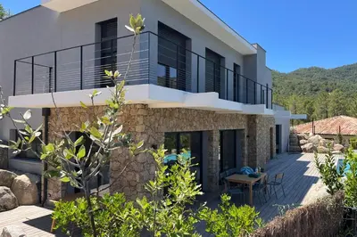 a house with a balcony and a patio at Villa Cime Di Machja in Sainte-Lucie de Porto-Vecchio