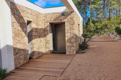 a stone house with a wooden walkway and a door at Villa Cime Di Machja in Sainte-Lucie de Porto-Vecchio