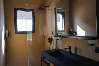a bathroom with a black sink and a mirror at Villa Cime Di Machja in Sainte-Lucie de Porto-Vecchio