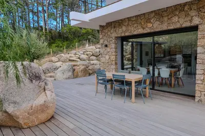 a wooden deck with a table and chairs on it at Villa Cime Di Machja in Sainte-Lucie de Porto-Vecchio