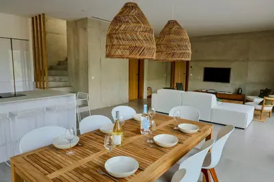 a dining room with a wooden table and white chairs at Villa Cime Di Machja in Sainte-Lucie de Porto-Vecchio