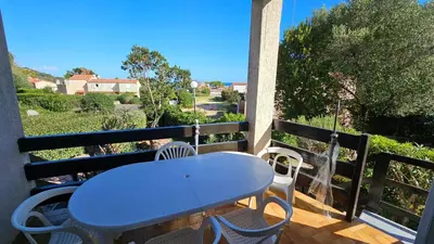 a blue table and chairs on a balcony with a view at CYRNEA 27- Plage à pieds - Clim-Wifi- Favone in Conca