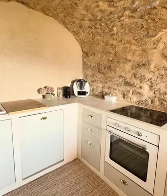a kitchen with white cabinets and a stone wall at Village House With Character In Corsica in Scolca