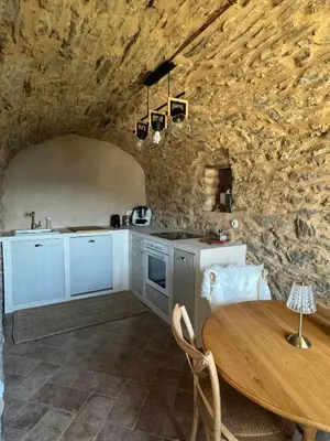 a kitchen with a table and a stone wall at Village House With Character In Corsica in Scolca