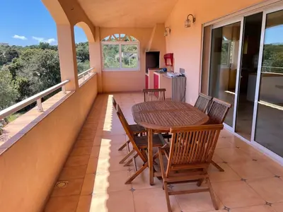 a balcony with a wooden table and chairs on it at Maison Bon Aria familiale vue mer 5 min plages in Porto-Vecchio