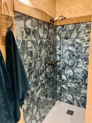 a bathroom with a shower with a tile wall at Magnifique Duplex au coeur de Cargèse in Cargèse