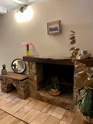 a living room with a stone fireplace and a mirror at Magnifique Duplex au coeur de Cargèse in Cargèse