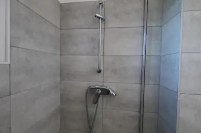a shower with a hose in a bathroom at U Bellu - Modernité et calme à deux pas de la mer in Lecci