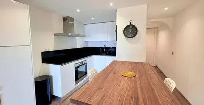 a kitchen with a wooden table and a clock on the wall at APPARTEMENT Vue MER TIUCCIA in Casaglione
