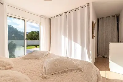 a bedroom with a bed and a large window at Villa Valle Pace Maria - Piscine Privée in Afa