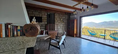 a living room with a large window with a mountain view at Maison de Charme Vue Exceptionnelle Mer & Montagne in Campomoro