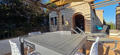 a wooden table and chairs on a deck at Maison de Charme Vue Exceptionnelle Mer & Montagne in Campomoro