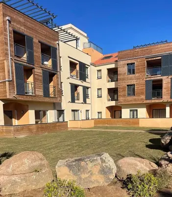an apartment complex with a lawn in front of a building at T2 cozy terrasse 40 m2 et pergola in Pianottoli-Caldarello