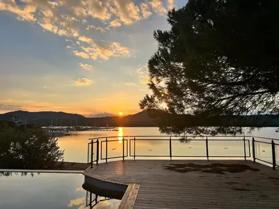 a sunset over a body of water with a dock at T2 cozy terrasse 40 m2 et pergola in Pianottoli-Caldarello