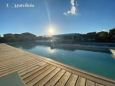 a large swimming pool with a wooden deck at logement piscine Porto Vecchio U Mateliciu in Lecci