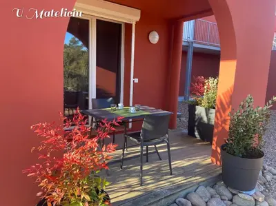 a patio with a table and chairs on a porch at logement piscine Porto Vecchio U Mateliciu in Lecci