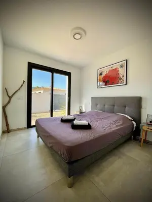 a bedroom with a large bed with a large window at Villa proche Saint Cyprien et Cala Rossa in Lecci