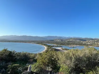 a view of a beach with mountains in the background at Villa proche Saint Cyprien et Cala Rossa in Lecci