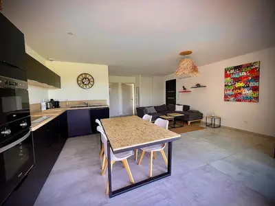 a kitchen and living room with a table and chairs at Villa proche Saint Cyprien et Cala Rossa in Lecci