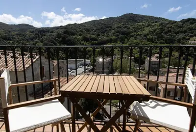 a wooden table and chairs on a balcony with a mountain at L'OMU DI CAGNA in Sartène