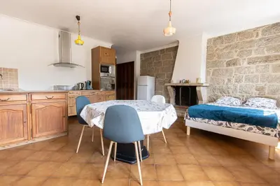a kitchen with a table and chairs and a bed at L'OMU DI CAGNA in Sartène