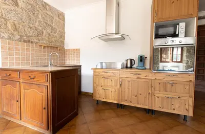 a kitchen with wooden cabinets and a sink and a microwave at L'OMU DI CAGNA in Sartène
