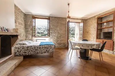a bedroom with a bed and a table and chairs at L'OMU DI CAGNA in Sartène