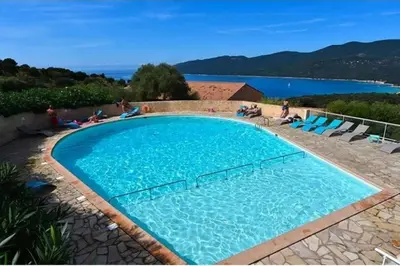 a large blue swimming pool with people sitting around it at Grand F2 clim wifi lave linge vue mer résidence piscine mer à pied in Serra-di-Ferro
